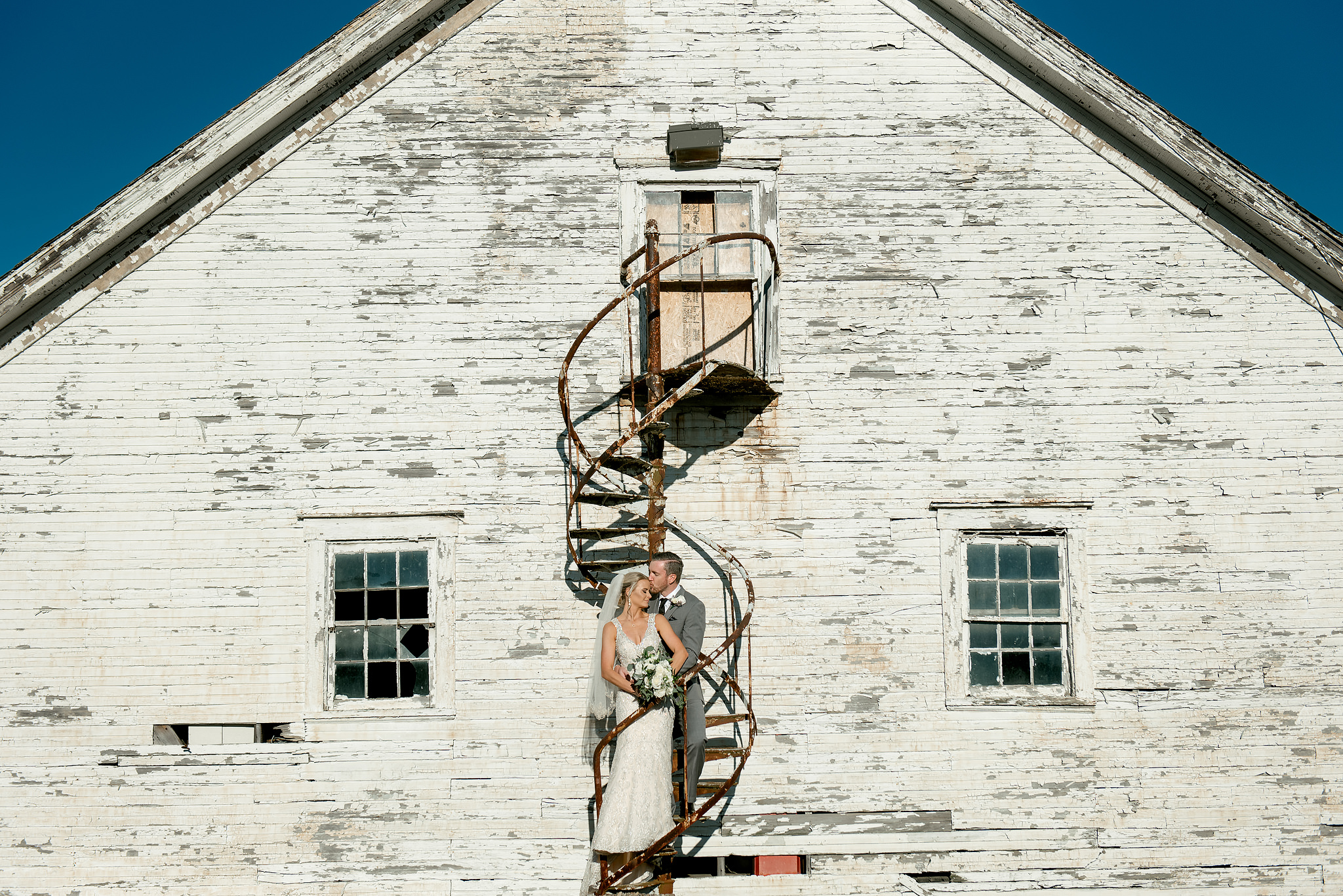 Wedding couple before the white barn at Montour Heights Country Club