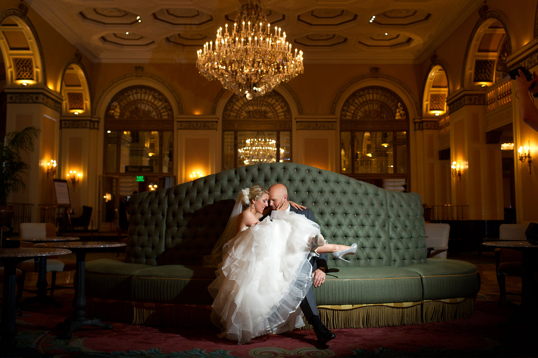 Bride and groom seated on a green sofa in the Omni William Penn