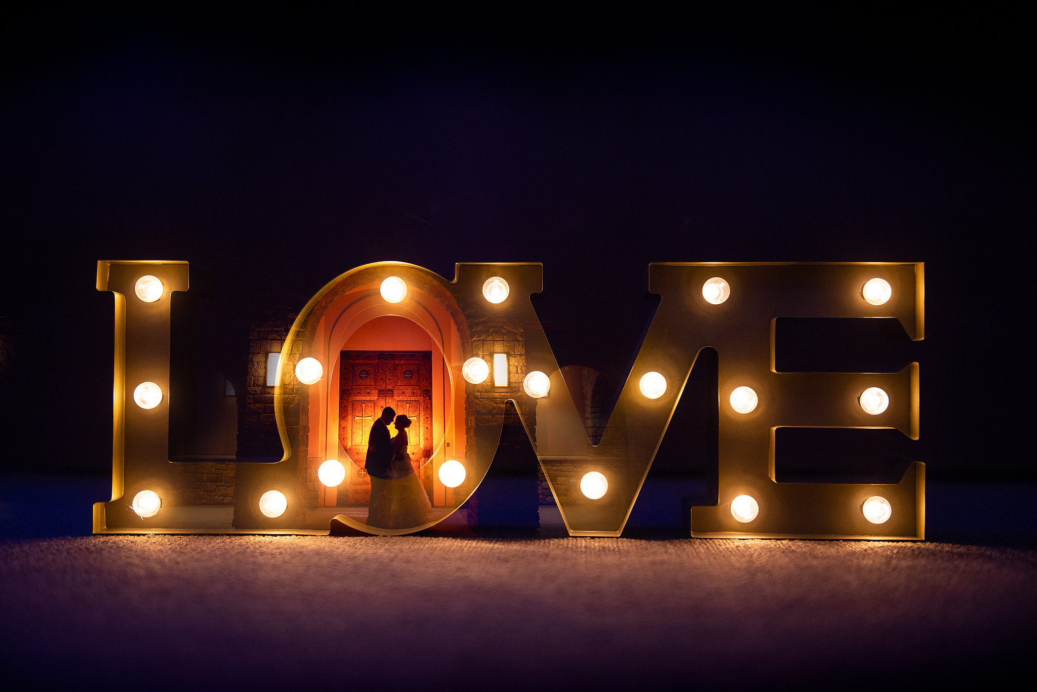 Wedding couple framed inside illuminated LOVE letters