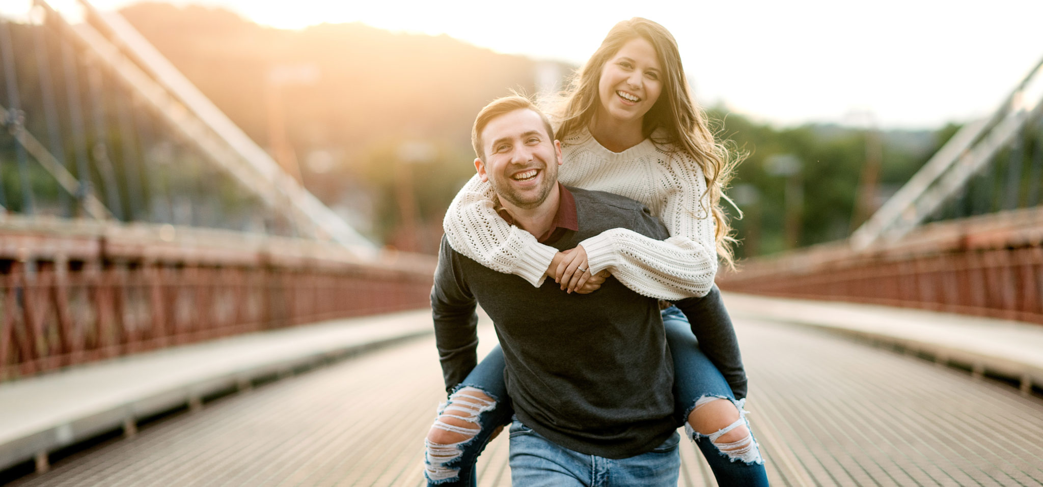 Engaged couple laughing together on a Pittsburgh bridge